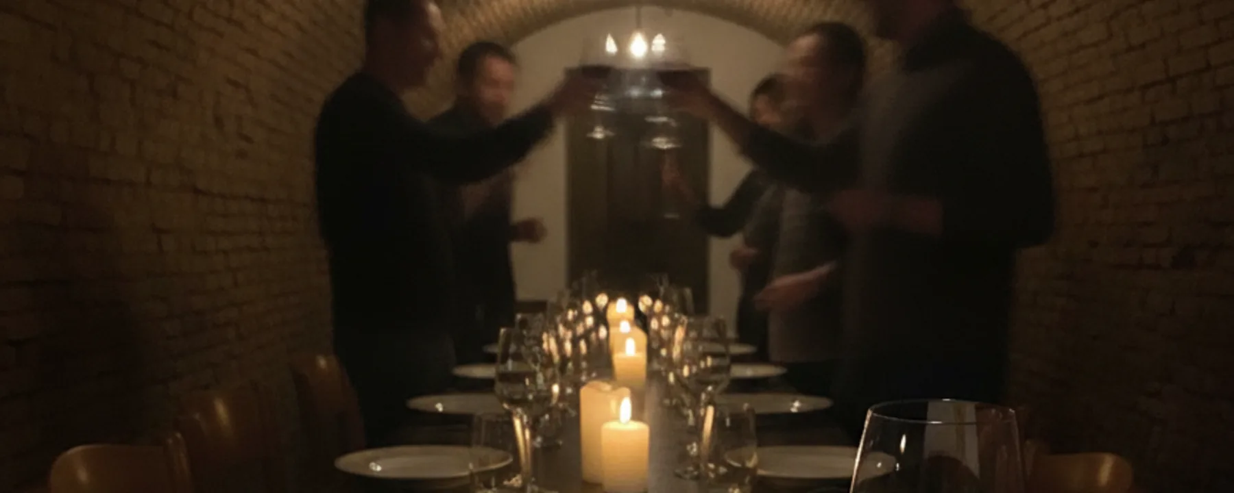 Gäste stossen im Gewölbekeller von Punto DiVino an einer langen Tafel mit Kerzen an